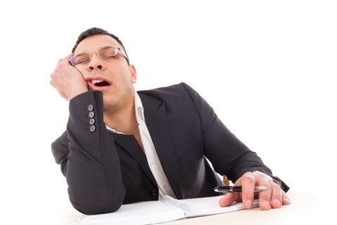 tired businessman yawning and sleeping at work with pen in hand