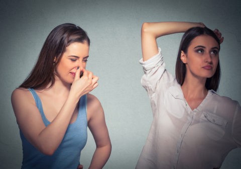 two women, one pinching nose something stinks, girls underarm isolated gray background
